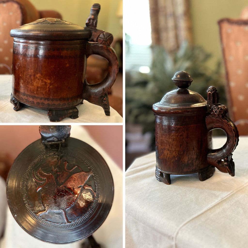 Two wooden beer steins from Norway. The larger one has a fox design engraved on the lid. They are on a table covered in white cloth.