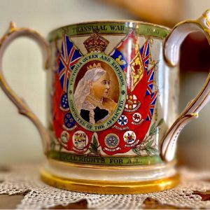 A three part image. On the top there is an image of a cup with two handles. On the side there is a picture of Queen Victoria. Under there is are two images of the cup. One image has a a list of politicians and their images on the back. On the other side there is an image of Britannia.