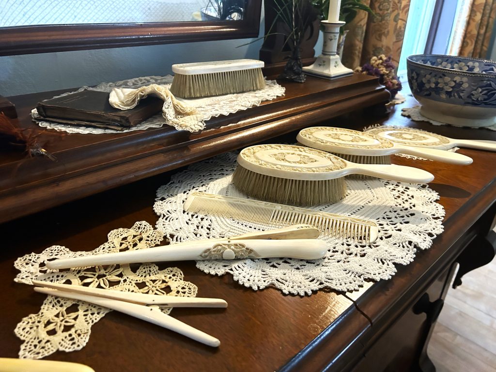 An image of a two tiered dressing table with ivory set of combs, brushes, glove stretcher, etc.