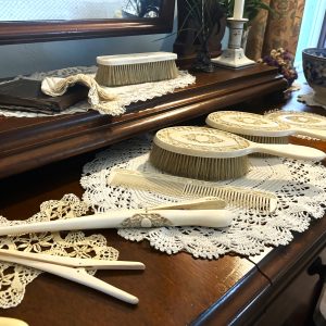 An image of a two tiered dressing table with ivory set of combs, brushes, glove stretcher, etc.