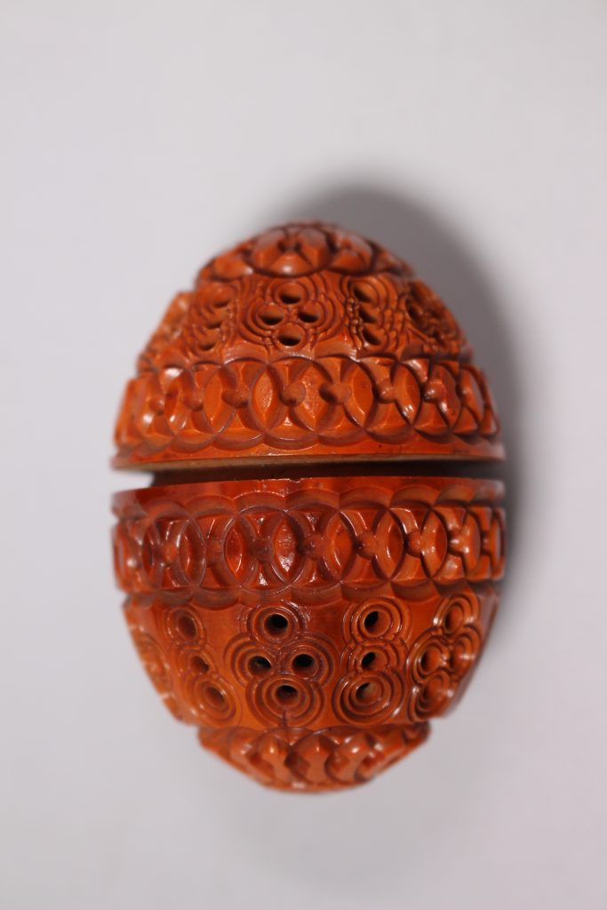 An ornate red egg with cutouts.