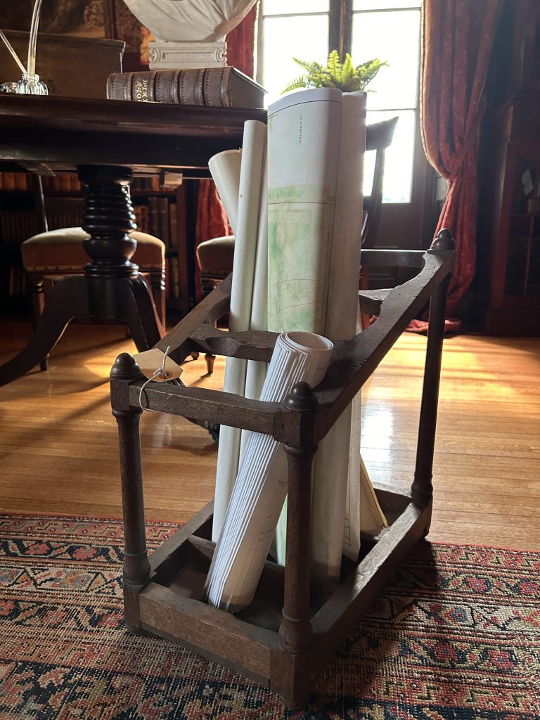 An image of a wooden stand. Inside the frame there are rolled up papers.