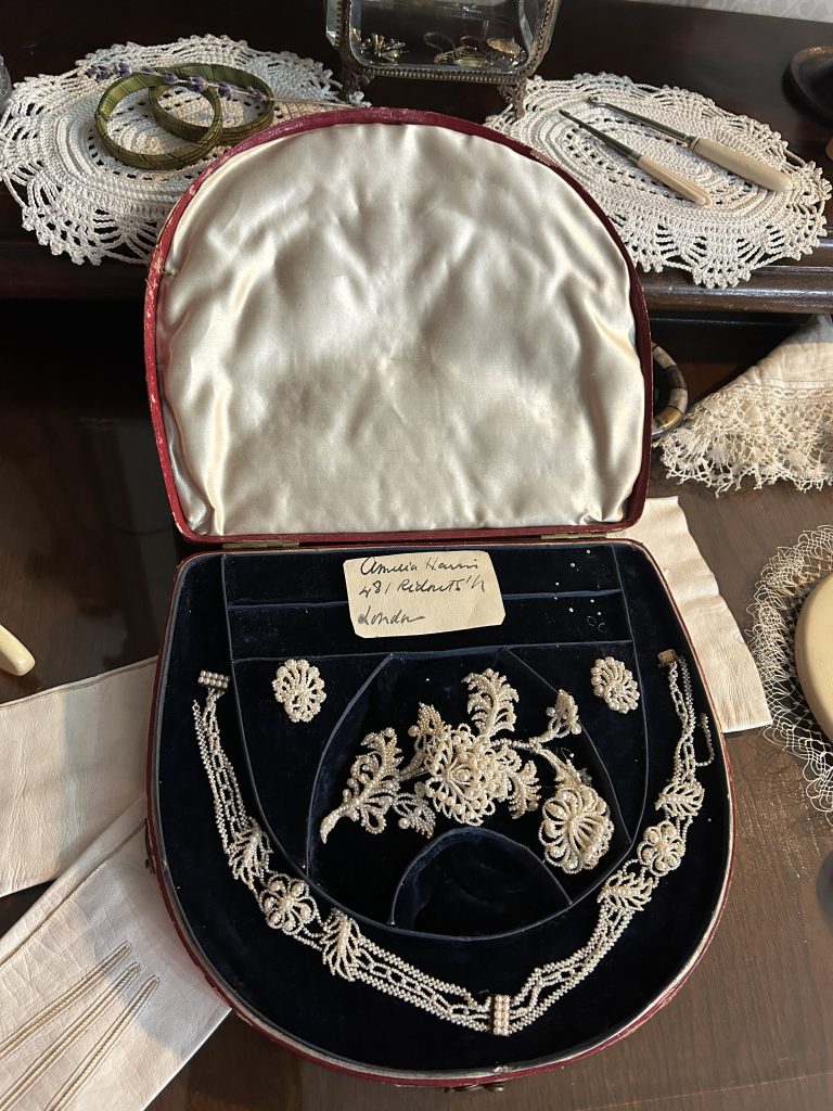An image of a necklace made of small pearls as well as a pair of earrings inside a blue velvet lined case.