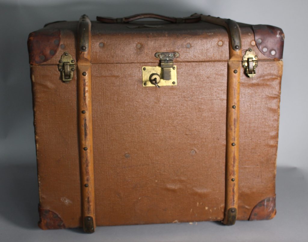 An image of a large brown suitcase with brass locks at the front.