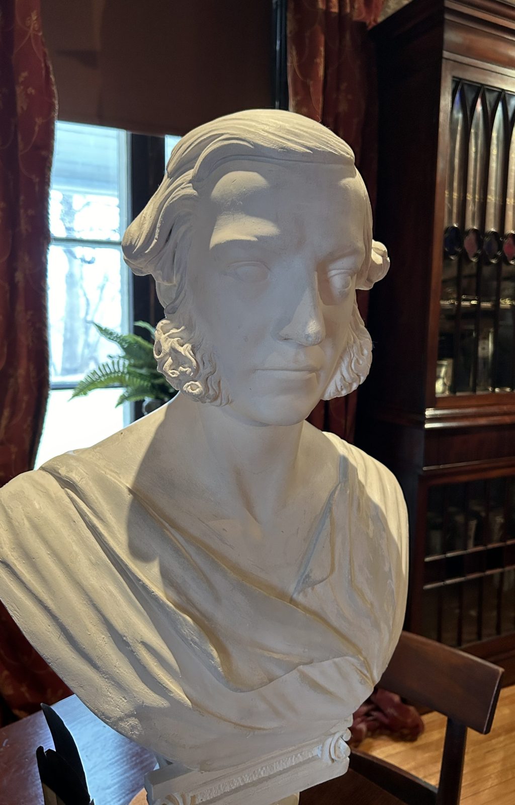 An image of a plaster bust of a man. The man has large sideburns and a toga draped over the shoulders.
